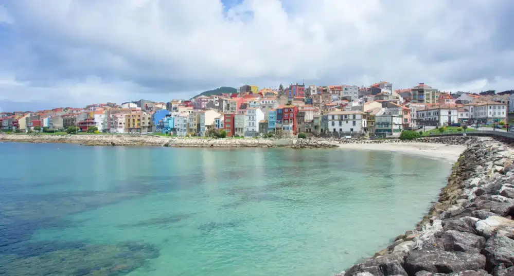 Vista de una costa con casas coloridas y playa tranquila bajo un cielo nublado en pontevedra