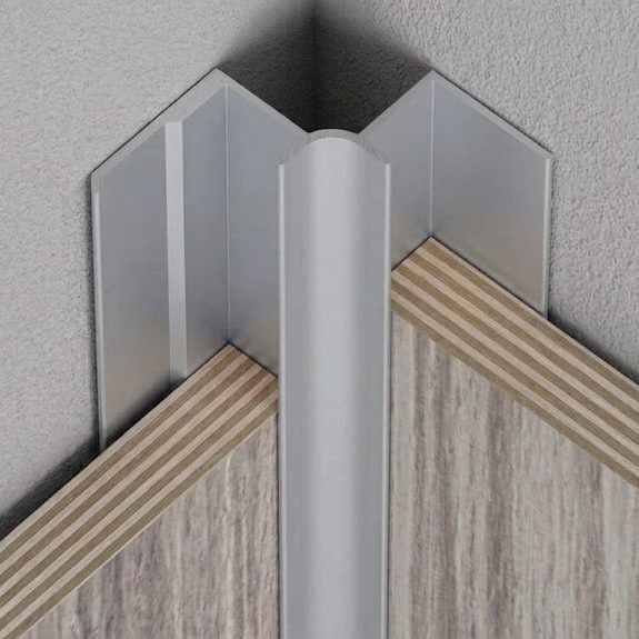 Esquina de placas decorativas con perfil aluminio mate Superficie de placas decorativas de mármol claro con vetas grises con un perfil de aluminio en la esquina