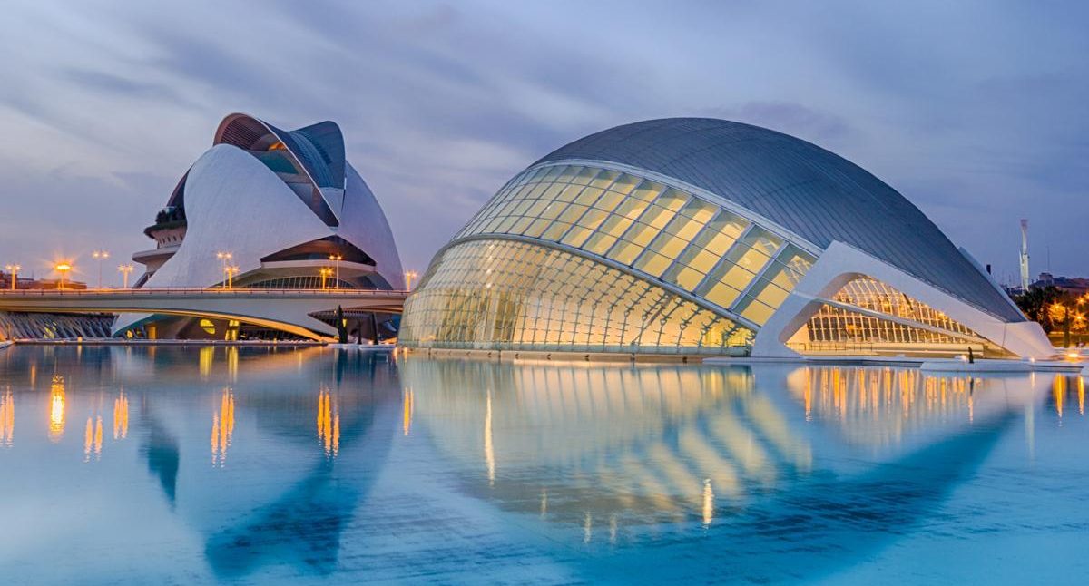 Edificios modernos reflejados en el agua al atardecer en la Ciudad de las Artes y las Ciencias.