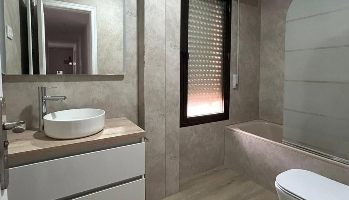 Interior moderno con mesa, sillas, y decoración en microcemento claro mate.