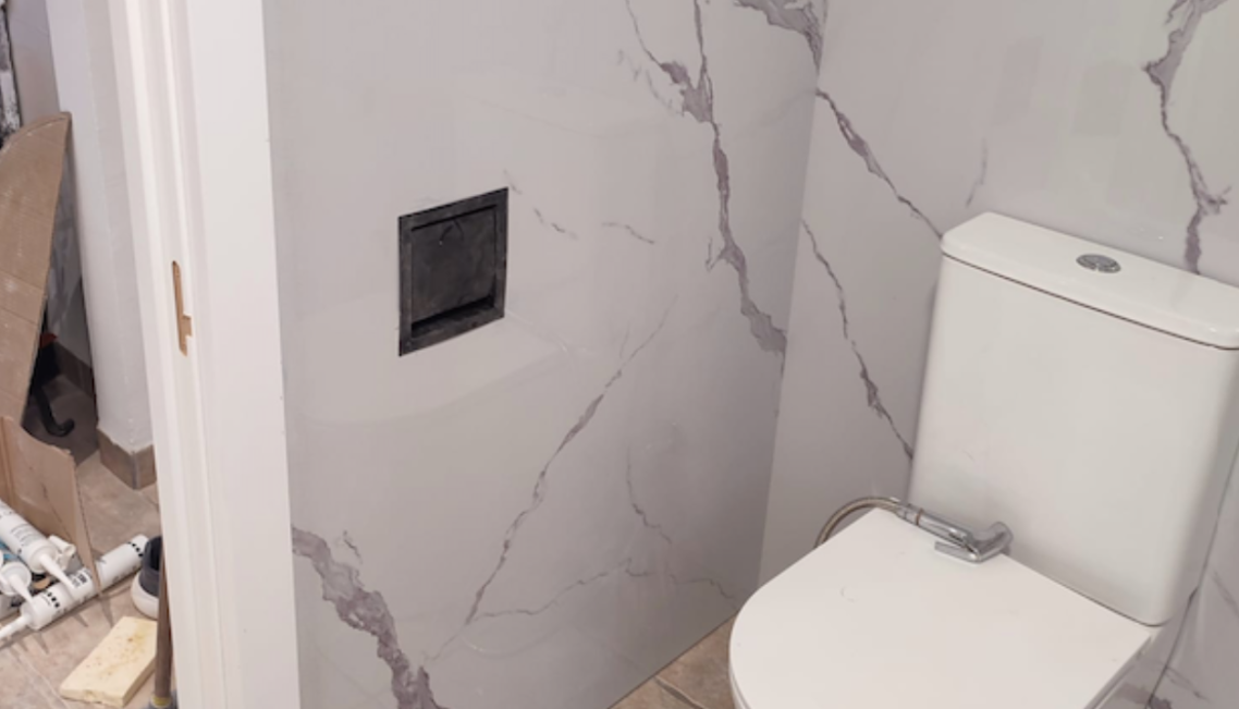 Baño moderno con bañera, paredes de mármol blanco y detalles en negro.