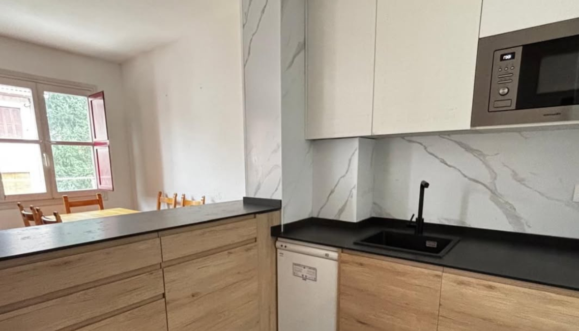 Interior moderno con mesa, sillas, y decoración en microcemento claro mate.