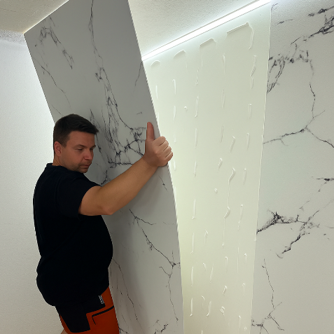 Hombre cogiendo una placa decorativa con diseño de mármol instalandola en la pared