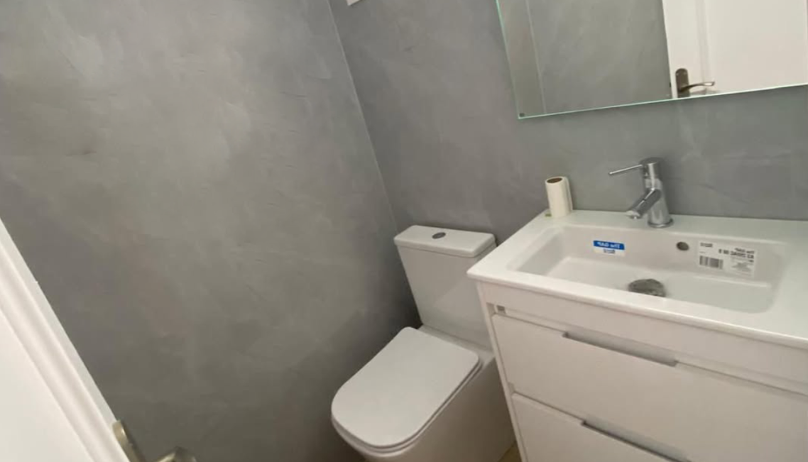 Interior moderno con mesa, sillas, y decoración en microcemento claro mate.