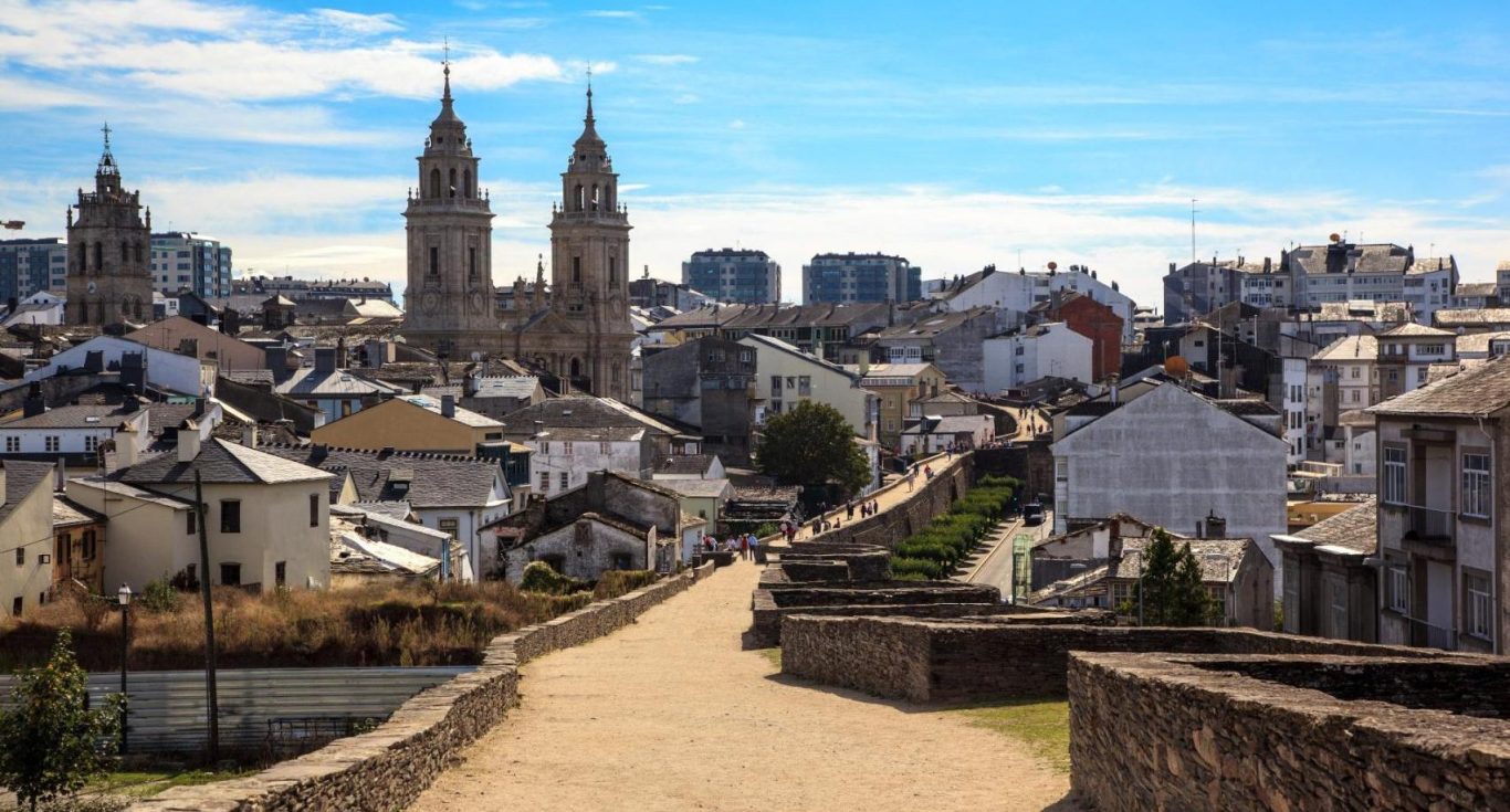 Vista panorámica de una ciudad con torres, edificios y el cielo azul.