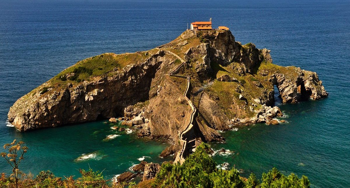 Isla con una ermita en la cima, rodeada de agua azul y acantilados en VIZCAYA