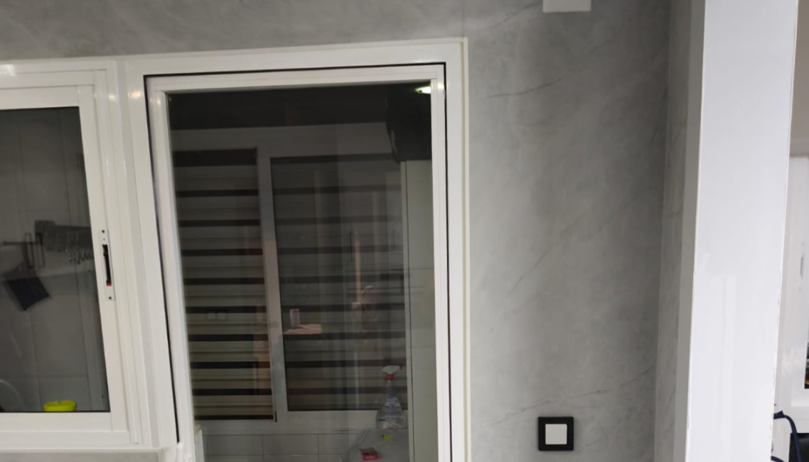 Baño moderno con piedra beige texturizada y lavabo contemporáneo.