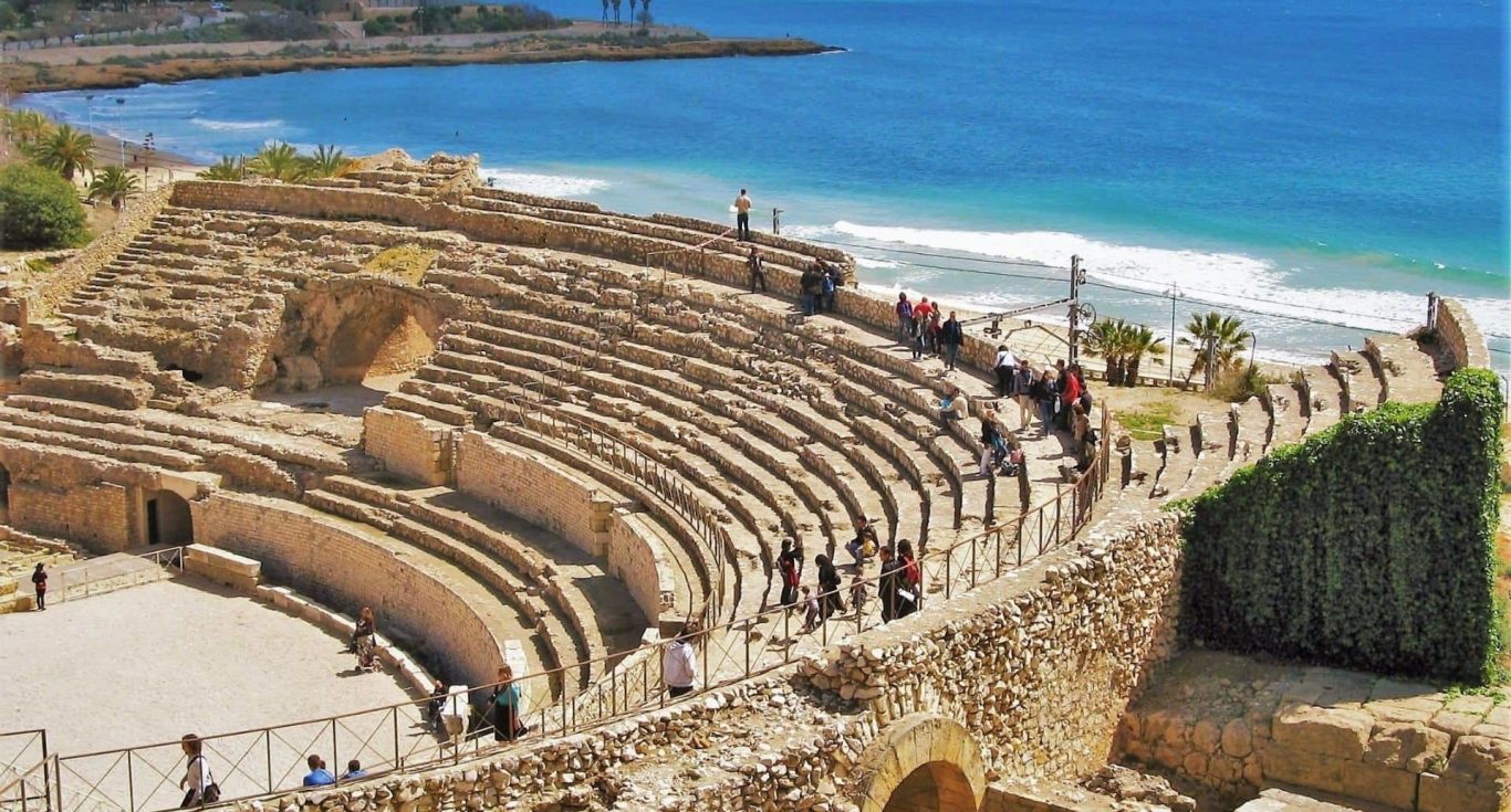 Anfiteatro antiguo junto al mar, rodeado de turistas y vegetación en TARRAGONA.