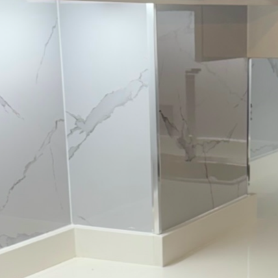 Superficie de placas decorativas de mármol claro con vetas grises con un perfil de aluminio en la esquina